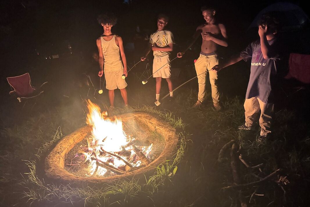 Campers roasting marshmallows around a campfire at night