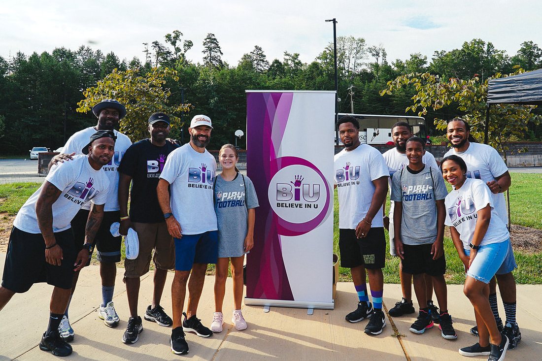 A large group of students and volunteers in Believe In U shirts posing outdoors
